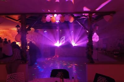 Salle de réception avec éclairage coloré, projecteurs violets et décorations suspendues, ambiance festive.