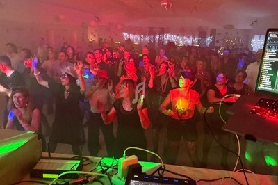 Vue depuis une table de mixage sur une foule dansante dans une salle éclairée par des lumières colorées.
