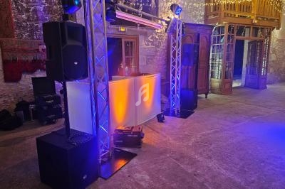 Installation de matériel de sonorisation et d'éclairage dans une salle avec murs en pierre et guirlandes lumineuses.