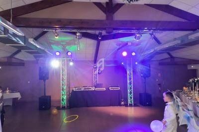 Salle de réception décorée avec éclairages colorés, piste de danse et matériel de sonorisation installé.