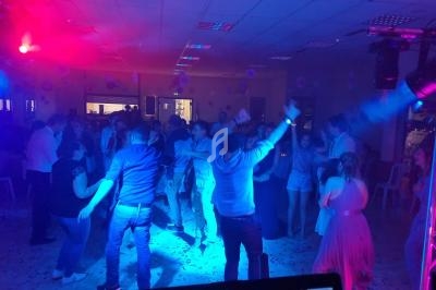 Groupe de personnes dansant dans une salle éclairée par des lumières colorées lors d'une soirée festive.