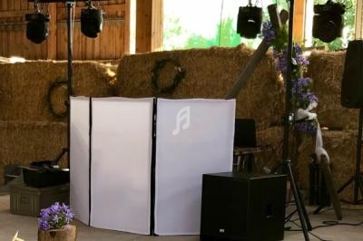 Installation de matériel de sonorisation et éclairage dans une grange décorée de bottes de foin et de fleurs violettes.