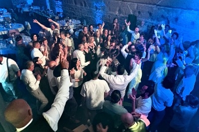 Groupe de personnes dansant et célébrant dans une salle éclairée par des lumières bleues.
