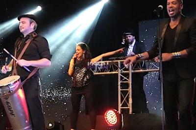 Des musiciens et une chanteuse se produisent sur scène sous des éclairages colorés.