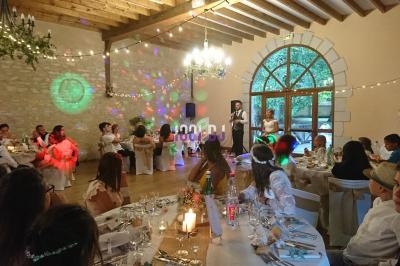 Salle de réception décorée pour un mariage, avec invités assis à table et un couple faisant un discours.