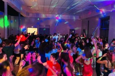 Des personnes dansent dans une salle éclairée par des lumières colorées lors d'une soirée festive.