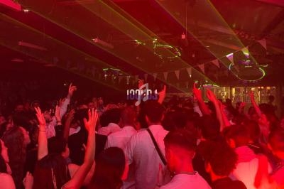 Foule dansant sous des lumières rouges et des lasers dans une ambiance festive en intérieur.