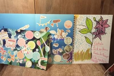 Trois cartes créatives décorées avec des dessins, autocollants et messages manuscrits colorés sur une surface en bois.