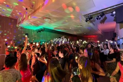 Personnes dansant dans une salle éclairée par des lumières colorées, ambiance festive et animée.