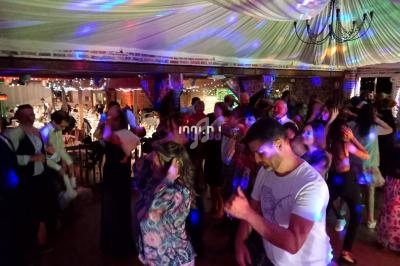 Groupe de personnes dansant sous des lumières colorées dans une salle décorée pour une fête.