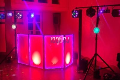 Installation de matériel de DJ avec éclairage coloré et projecteurs dans une salle sombre.