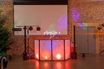 Installation de matériel de son et lumière dans une salle en pierre, avec un écran de projection et un sapin décoratif.