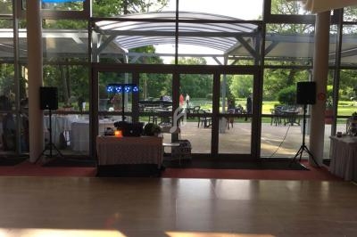 Salle lumineuse avec baie vitrée donnant sur un jardin, équipée d'une table de mixage et de haut-parleurs.