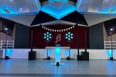 Scène décorée avec des lumières bleues, une table lumineuse au centre et un rideau rouge en arrière-plan.