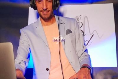 Un DJ portant un casque audio mixe de la musique sur une table de mixage, avec un fond lumineux.