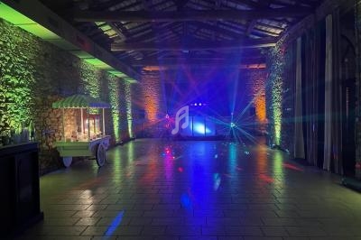 Salle en pierre illuminée par des jeux de lumière colorés, avec un stand de confiseries sur la gauche.