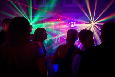 Personnes dansant dans une ambiance festive avec des jeux de lumière colorés et des lasers.
