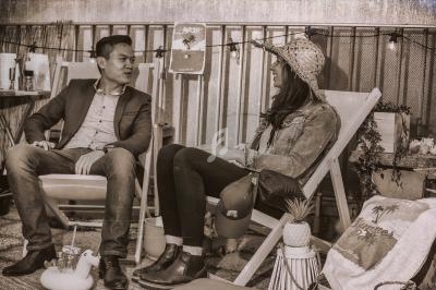 Deux personnes discutent assises sur des chaises longues dans un espace extérieur décoré de manière conviviale.