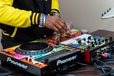 Un DJ utilise une console de mixage colorée avec des platines et des boutons de réglage.