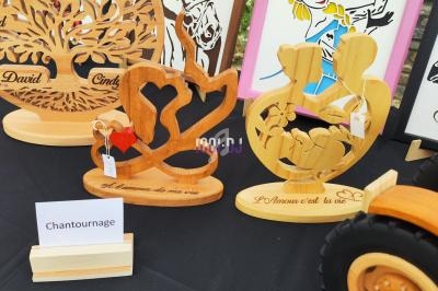 Objets en bois sculpté exposés sur une table, incluant des décorations gravées et des cadres illustrés.