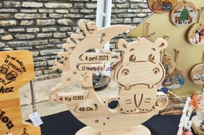 Figurine en bois en forme de lune et d'hippopotame, personnalisée avec des informations de naissance, exposée sur un stand…