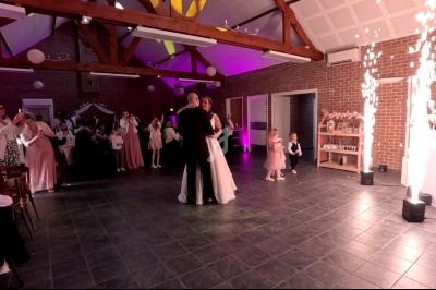 Un couple danse au centre d'une salle de réception décorée, entouré d'invités et d'effets lumineux.