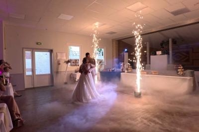 Deux personnes dansent dans une salle décorée, entourées de fumée et d'effets pyrotechniques.