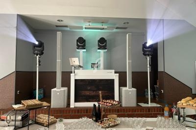 Table garnie de mets et boissons devant une scène équipée d'un stand de DJ avec éclairages et enceintes.