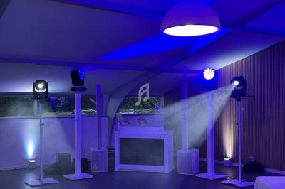 Installation de lumières et d'équipements de sonorisation dans une salle avec éclairage bleu tamisé.