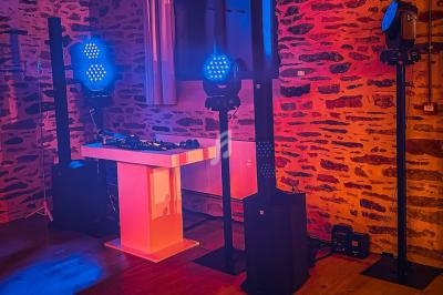 Installation de matériel de sonorisation et d'éclairage dans une salle aux murs en pierre, ambiance lumineuse colorée.