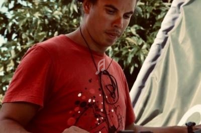 Homme portant un t-shirt rouge, utilisant un équipement électronique en extérieur, avec des arbres en arrière-plan.