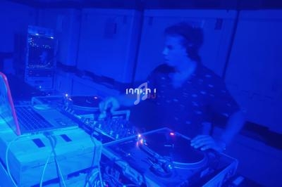 Un DJ mixant de la musique sur des platines dans une ambiance lumineuse bleutée.