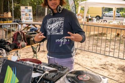 Un DJ mixe sur une table de mixage sous une tente lors d'un événement en plein air.