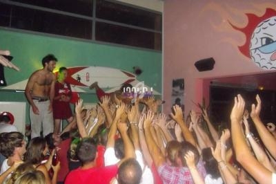 Groupe de personnes levant les bras dans une ambiance festive à l'intérieur d'une salle colorée.