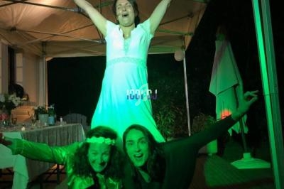 Trois femmes posant joyeusement sous une tente éclairée par des lumières colorées lors d'un événement en soirée.