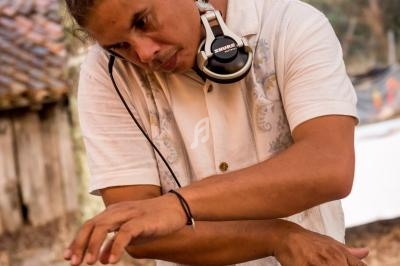 Un DJ mixant des vinyles en plein air, concentré sur ses gestes, avec un casque autour du cou.