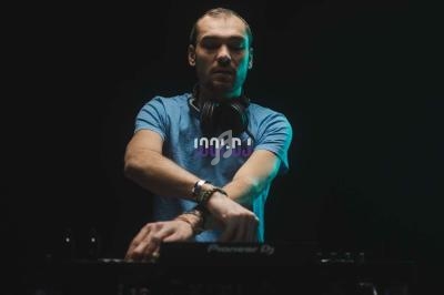 Un DJ concentré mixe de la musique sur une table de mixage dans une ambiance sombre avec un éclairage subtil.