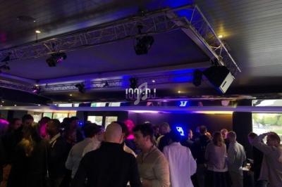 Des personnes discutent dans un espace intérieur moderne avec éclairage tamisé et équipements audiovisuels visibles.