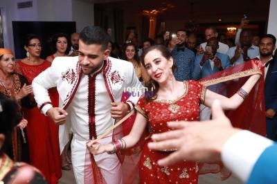Un couple danse en tenue traditionnelle lors d'une fête entourée d'invités qui les regardent et prennent des photos.