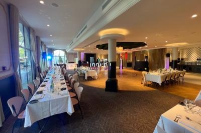 Salle de réception élégante avec tables dressées, éclairage coloré et espace central dégagé pour des événements.