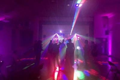 Personnes dansant dans une salle sombre éclairée par des lumières colorées et des faisceaux lumineux.