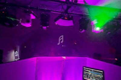 Équipement de DJ avec ordinateur portable et éclairage coloré dans une ambiance de soirée.