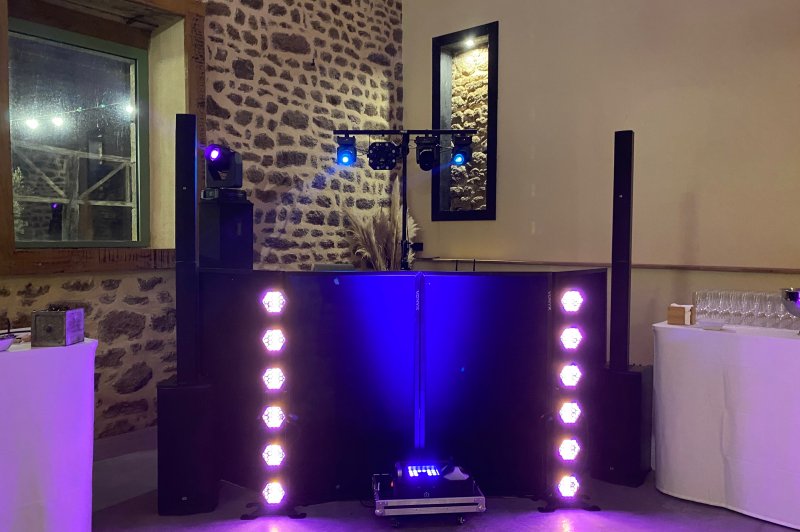 Installation de matériel de sonorisation et éclairage avec projecteurs LED dans une salle aux murs en pierre.
