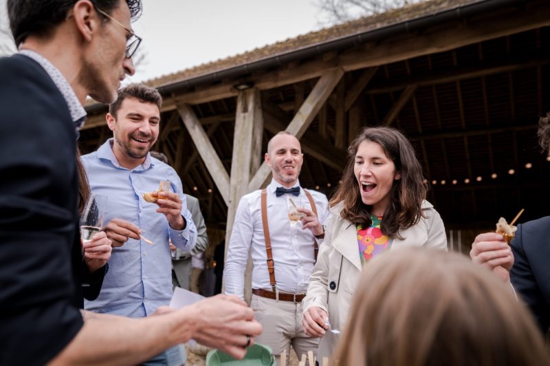 Un groupe de personnes souriantes partage un moment convivial en extérieur près d'une structure en bois.