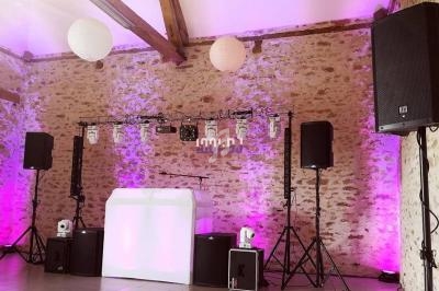 Installation de matériel de sonorisation et éclairage dans une salle en pierre avec des lumières roses et blanches.