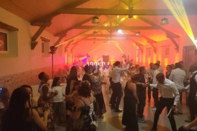 Des personnes dansent dans une salle éclairée de lumières chaudes, avec un plafond en bois et des poutres apparentes.