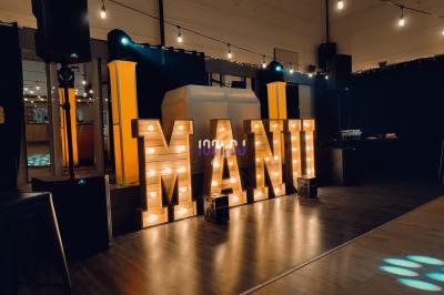 Lettres lumineuses formant le mot ’MARIAGE’ dans une salle décorée avec des guirlandes et un éclairage chaleureux.