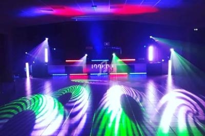 Salle de danse vide avec jeux de lumières colorées projetant des motifs sur le sol.