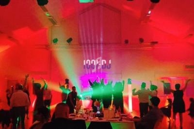 Des personnes dansent sous des lumières colorées dans une salle festive avec une ambiance de soirée animée.