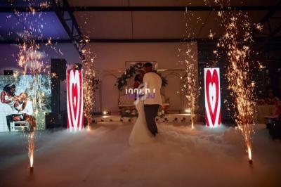 Un couple danse au milieu d'une piste entourée de fumée, de fontaines d'étincelles et d'écrans lumineux en arrière-plan.